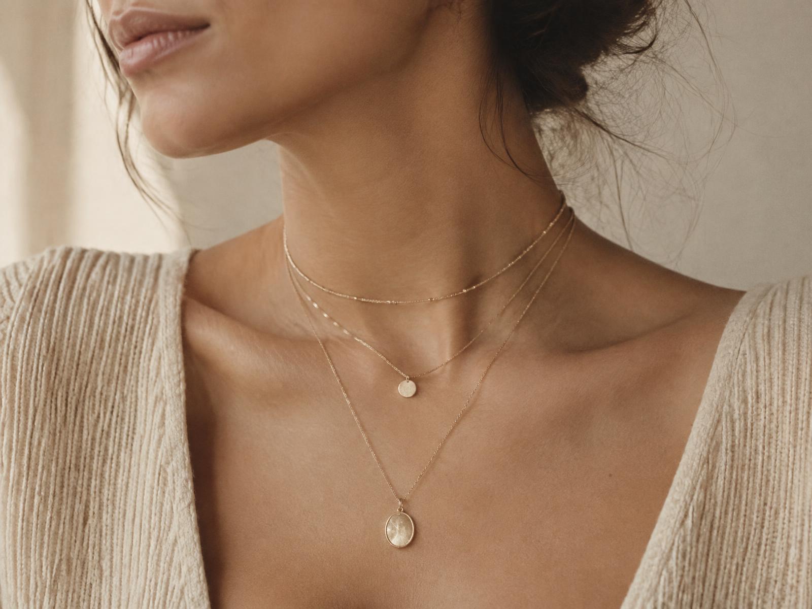 Layered minimal gold necklaces worn on a neckline